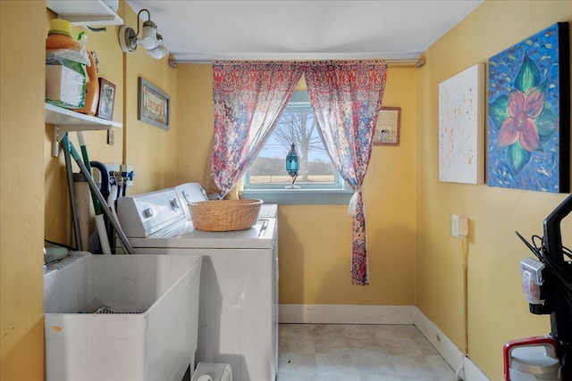 washroom featuring washing machine and clothes dryer, baseboards, a sink, and laundry area