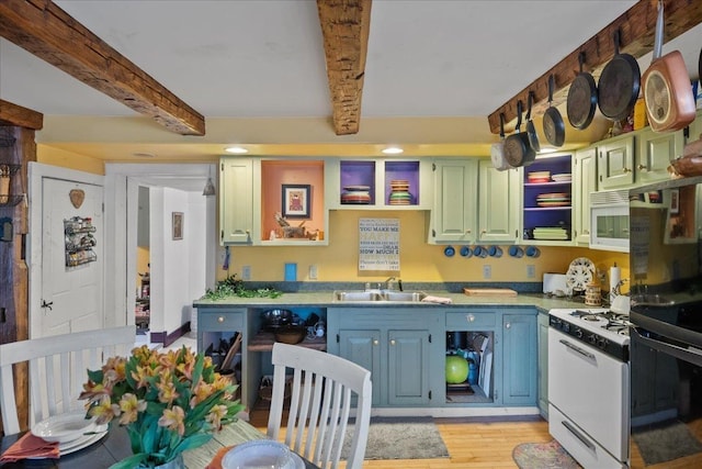 kitchen featuring light wood finished floors, light countertops, a sink, beamed ceiling, and white appliances