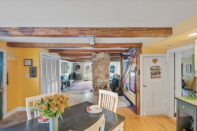 dining space with light wood-style flooring, baseboards, and beam ceiling