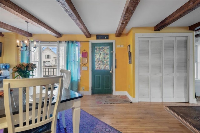 entryway with hardwood / wood-style flooring, an inviting chandelier, beamed ceiling, and baseboards