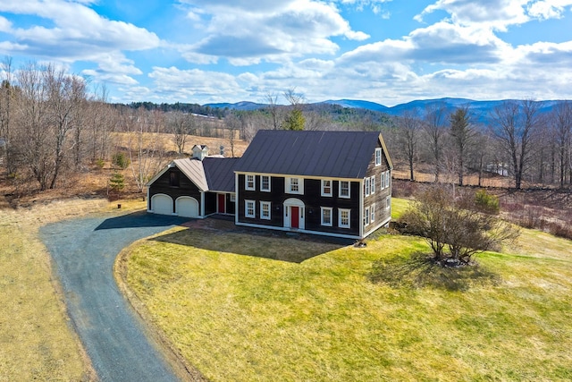 view of front of property featuring driveway, an attached garage, a mountain view, metal roof, and a standing seam roof