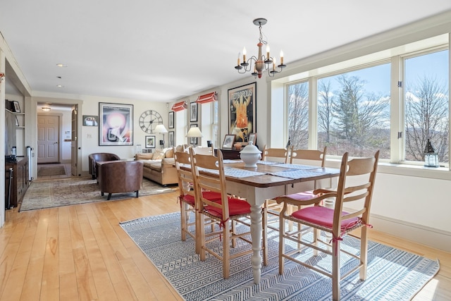 dining area featuring light wood finished floors, baseboards, and an inviting chandelier