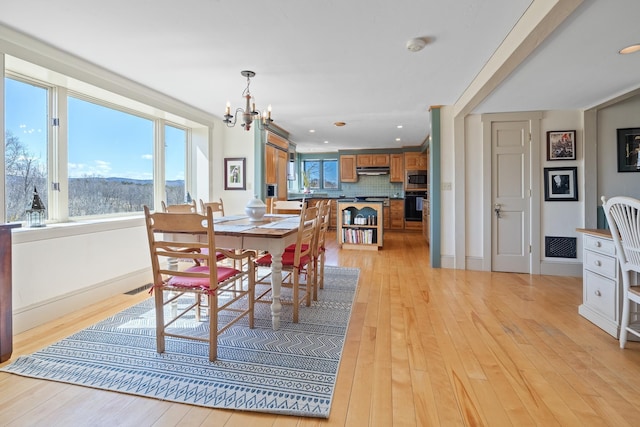 dining space featuring a chandelier, light wood finished floors, baseboards, and recessed lighting