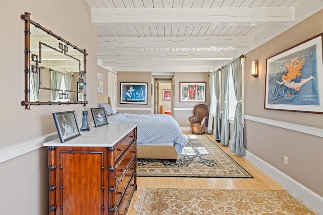 bedroom featuring light wood-type flooring, baseboards, beam ceiling, and wood ceiling