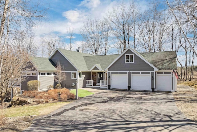 view of front facade with a chimney, driveway, a shingled roof, covered porch, and a garage