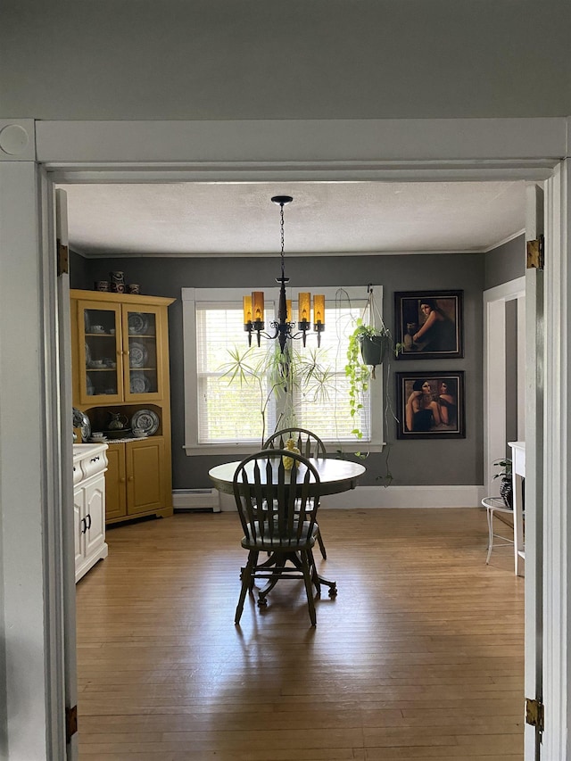 dining space featuring a chandelier, light wood-style floors, a baseboard radiator, and baseboards