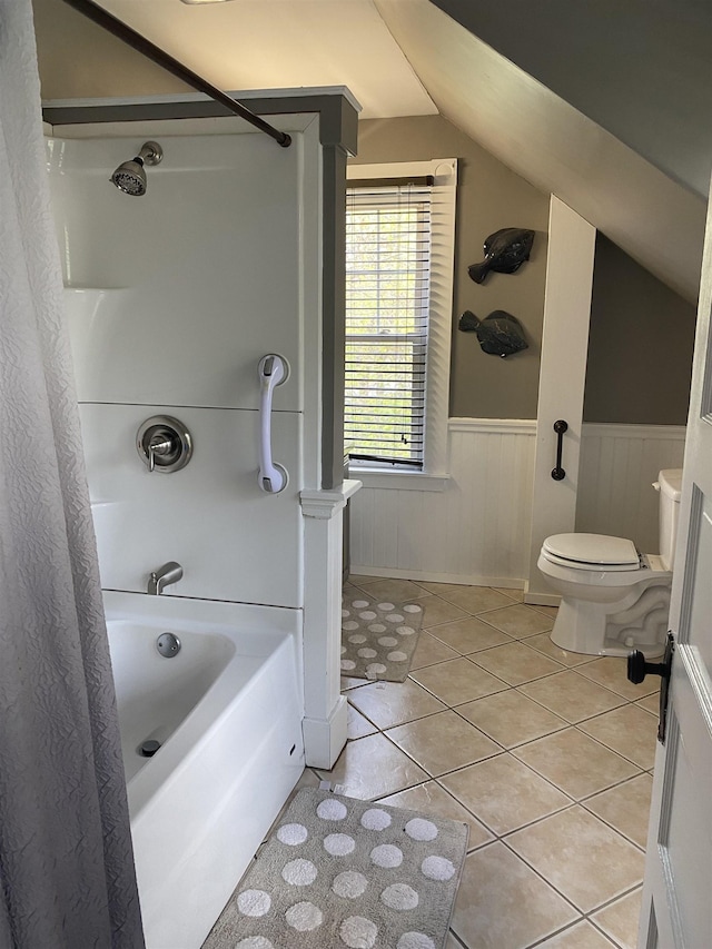 full bath with lofted ceiling, a wainscoted wall, tile patterned floors, bathing tub / shower combination, and toilet