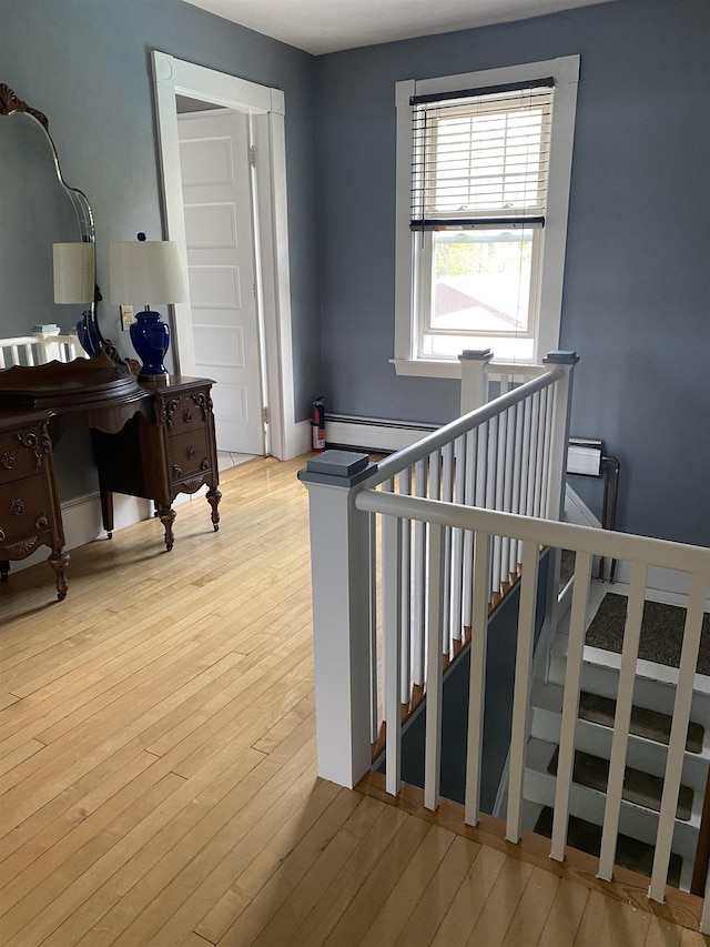 stairway with a baseboard radiator and wood-type flooring