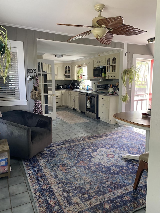 kitchen with glass insert cabinets, crown molding, stainless steel appliances, and light tile patterned floors