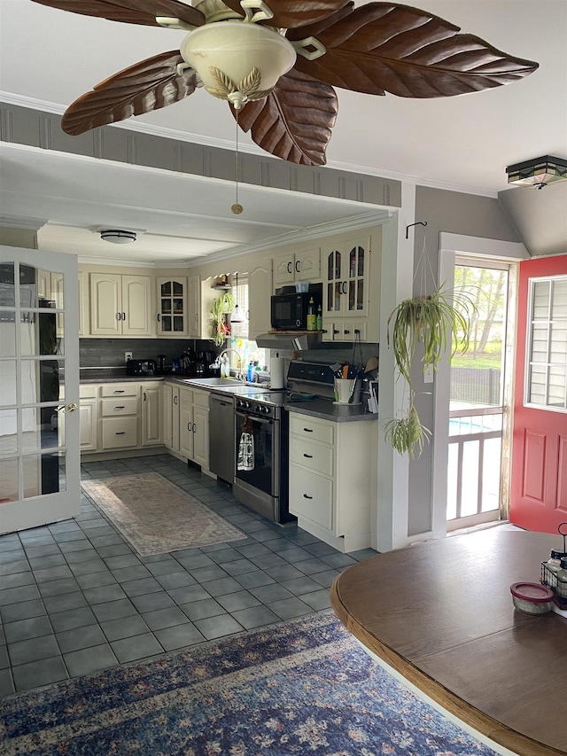 kitchen featuring stainless steel appliances, dark countertops, a sink, dark tile patterned floors, and glass insert cabinets