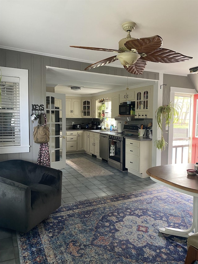kitchen with ornamental molding, stainless steel appliances, dark tile patterned floors, and glass insert cabinets