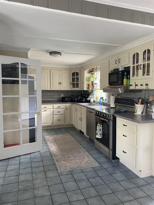 kitchen with cream cabinetry, crown molding, dark tile patterned floors, and stainless steel appliances