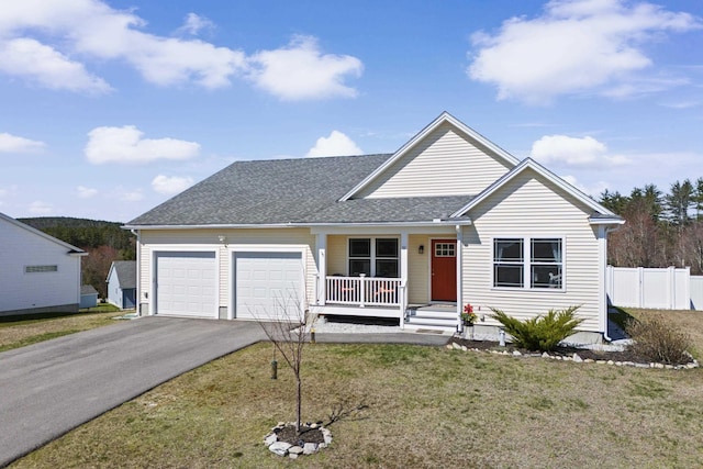 view of front facade featuring a front lawn, aphalt driveway, covered porch, an attached garage, and fence
