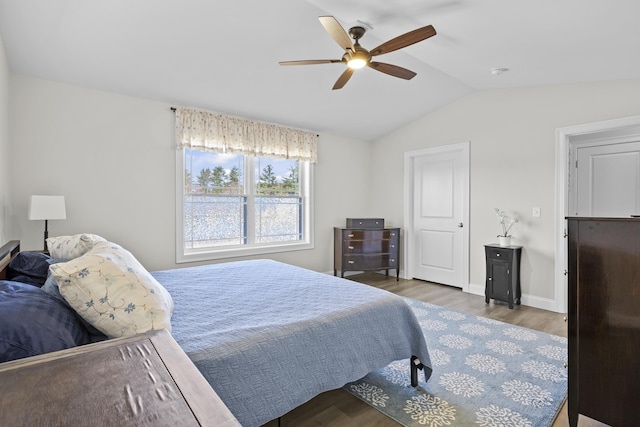 bedroom with vaulted ceiling, a ceiling fan, wood finished floors, and baseboards