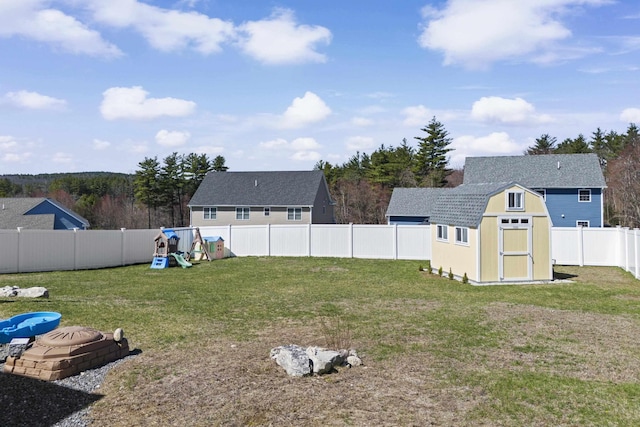 view of yard featuring a fenced backyard, a storage unit, an outbuilding, and a playground