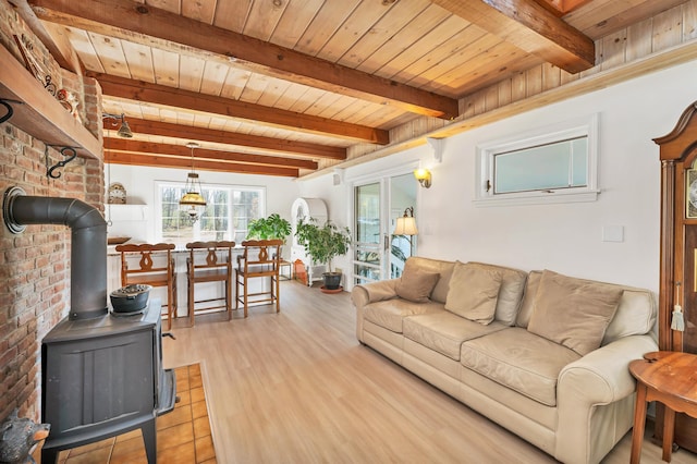 living area featuring wooden ceiling, a wood stove, beamed ceiling, and light wood-style flooring
