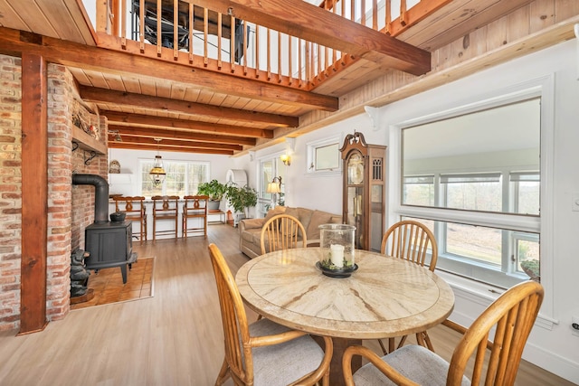dining area featuring beamed ceiling, wood finished floors, a wood stove, and wooden ceiling