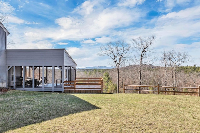 view of yard featuring a sunroom and a deck with mountain view