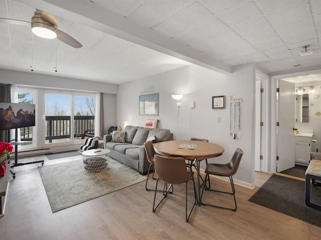 living area with baseboards, wood finished floors, and ceiling fan