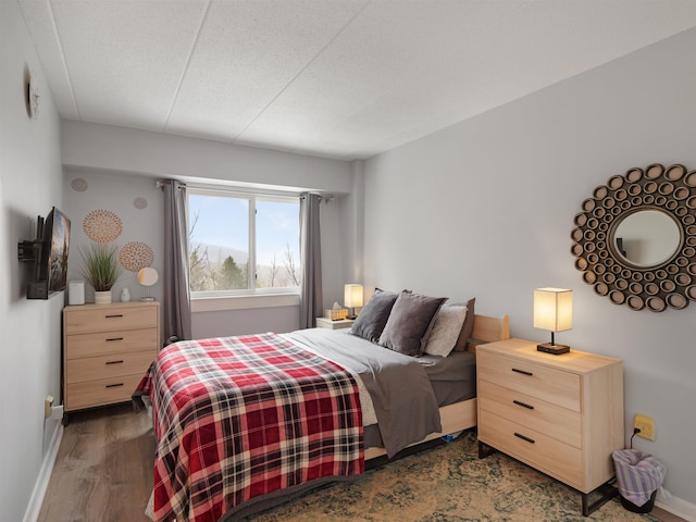 bedroom with baseboards and dark wood-type flooring