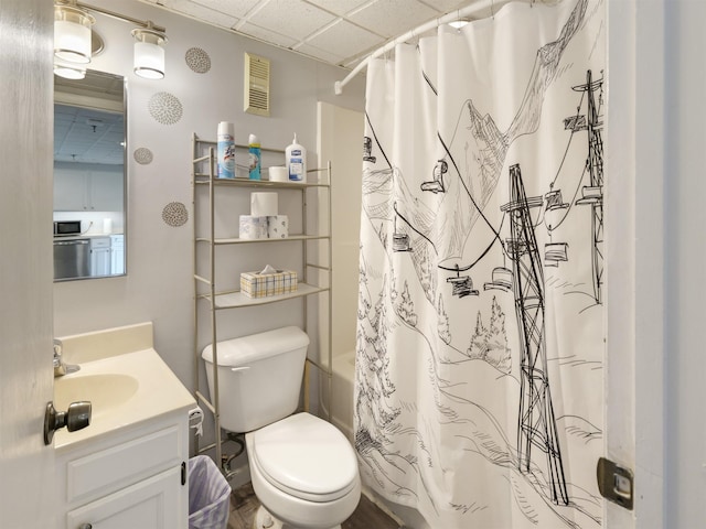 full bath with toilet, a drop ceiling, visible vents, shower / bathtub combination with curtain, and vanity