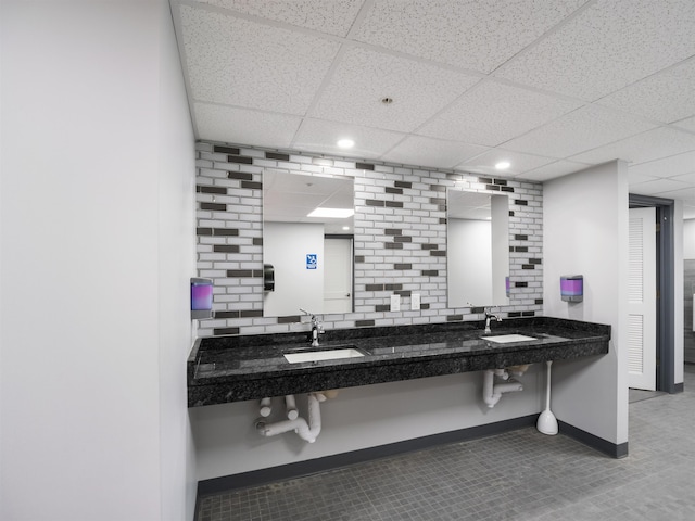 bathroom with baseboards, a drop ceiling, and recessed lighting