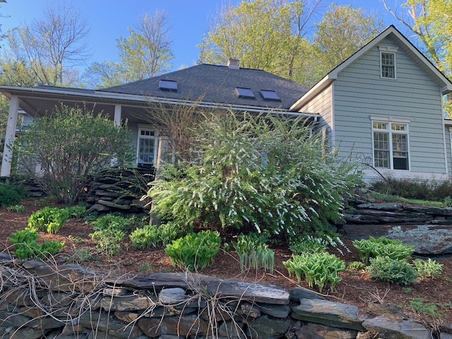 view of side of property featuring a shingled roof and a chimney