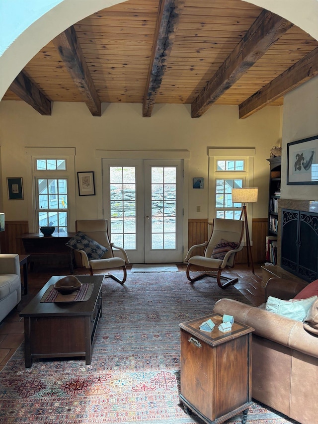 living room featuring wood ceiling, arched walkways, wainscoting, and beamed ceiling