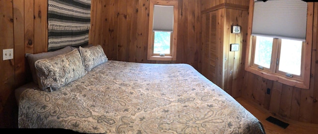 bedroom featuring visible vents, wood finished floors, and wood walls
