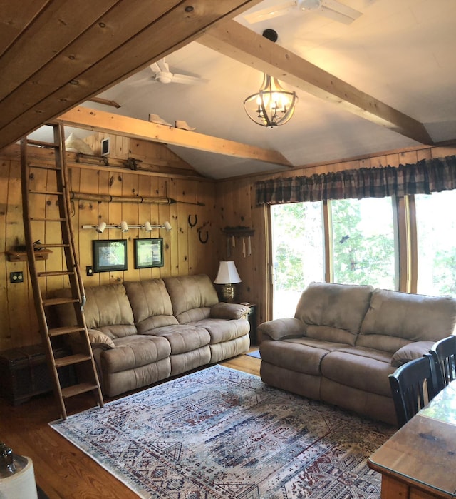 living room with lofted ceiling with beams, a ceiling fan, wood finished floors, and wooden walls