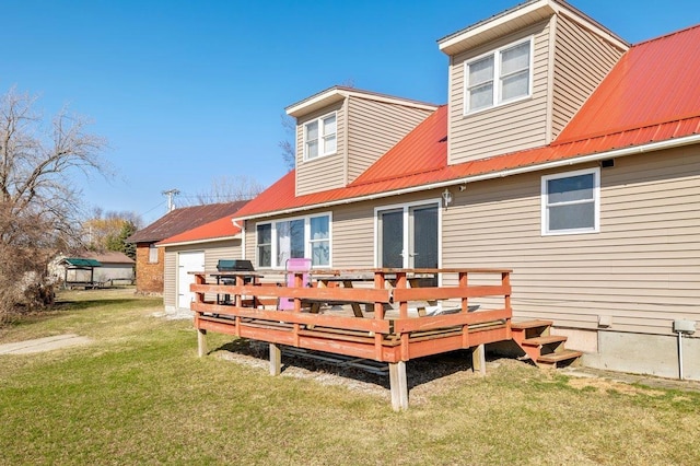 rear view of property featuring a lawn, metal roof, and a deck