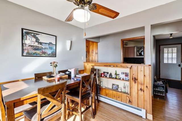 dining space with a baseboard heating unit, wood finished floors, and ceiling fan