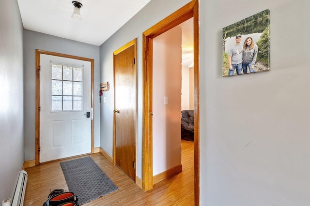 entryway with a baseboard heating unit, baseboards, and light wood finished floors