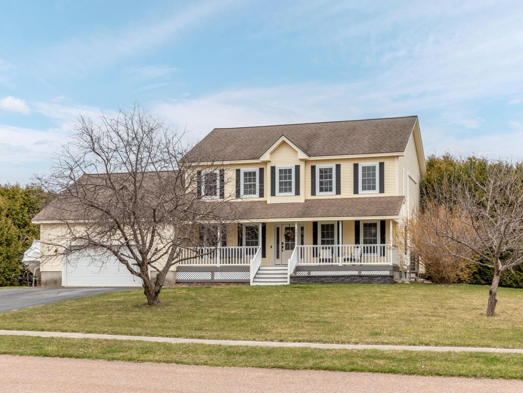 105 Casey Ln, Colchester, VT 05446 - colonial-style house with a porch, driveway, a front lawn, and a shingled roof