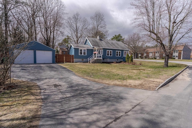 view of front of home featuring a detached garage, a chimney, a front lawn, fence, and an outbuilding