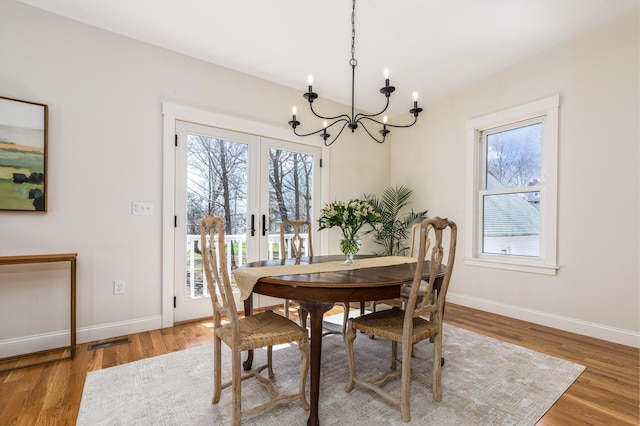 dining area with french doors, baseboards, visible vents, a notable chandelier, and wood finished floors