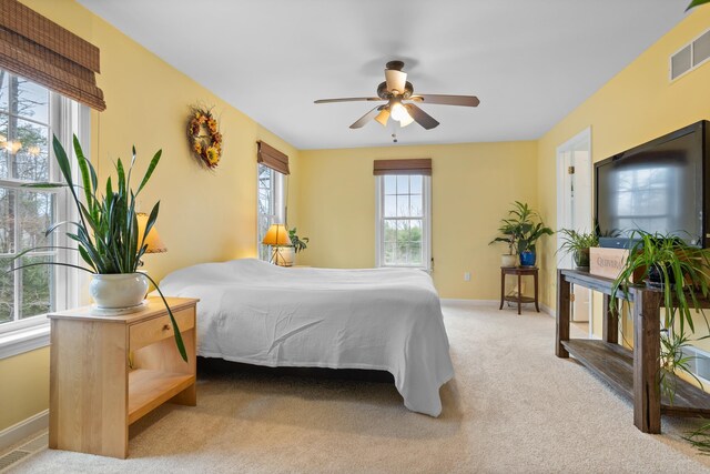 carpeted bedroom with visible vents, baseboards, and ceiling fan