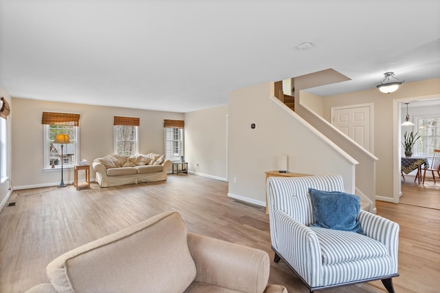 living area with light wood-style flooring, a healthy amount of sunlight, stairs, and visible vents