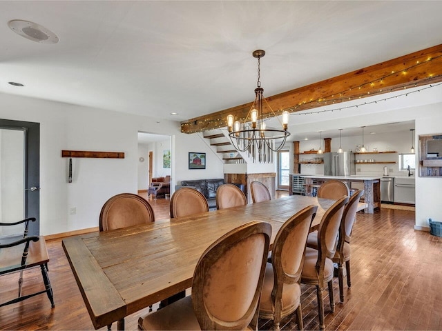 dining area with beamed ceiling, wood finished floors, stairs, and an inviting chandelier