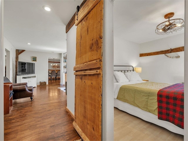 bedroom with recessed lighting, wood finished floors, a barn door, and an inviting chandelier