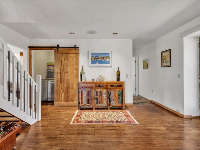 foyer entrance with a barn door, baseboards, wood finished floors, and recessed lighting