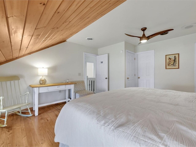 bedroom with vaulted ceiling, visible vents, a ceiling fan, wood finished floors, and wooden ceiling