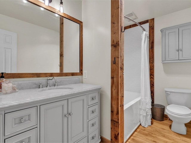 full bathroom featuring toilet, visible vents, wood finished floors, shower / bath combination with curtain, and vanity