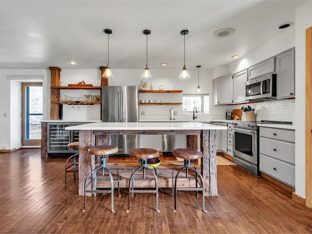 kitchen with a kitchen bar, open shelves, stainless steel appliances, and light countertops