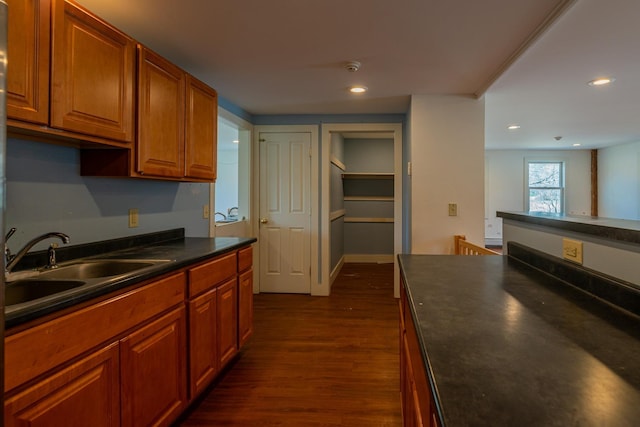 kitchen with dark countertops, dark wood-style flooring, a sink, and recessed lighting