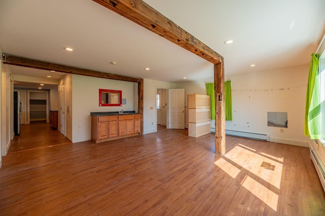 unfurnished living room with baseboards, baseboard heating, wood finished floors, and recessed lighting