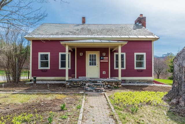 view of front facade featuring a chimney and a shingled roof