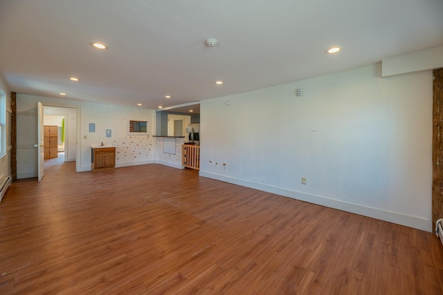 unfurnished living room featuring recessed lighting, wood finished floors, and baseboards