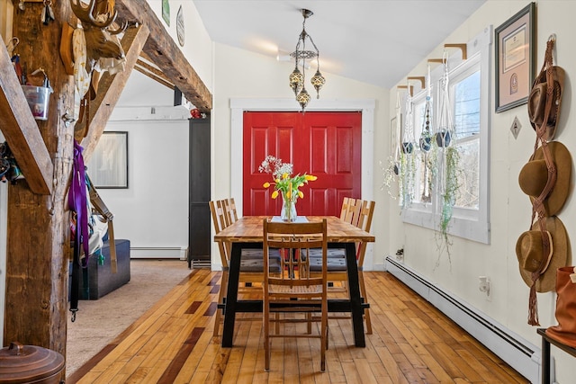 dining room featuring baseboard heating, vaulted ceiling, and light wood-style floors