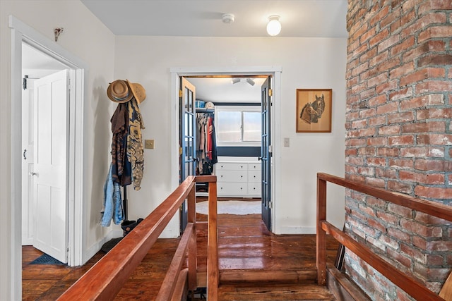 hallway featuring baseboards, dark wood-style flooring, and an upstairs landing